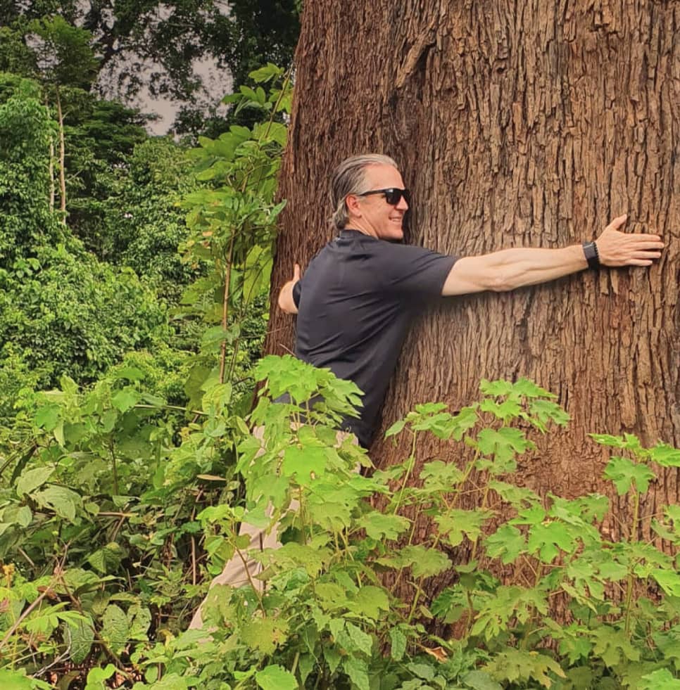 Red River employee hugging giant tree