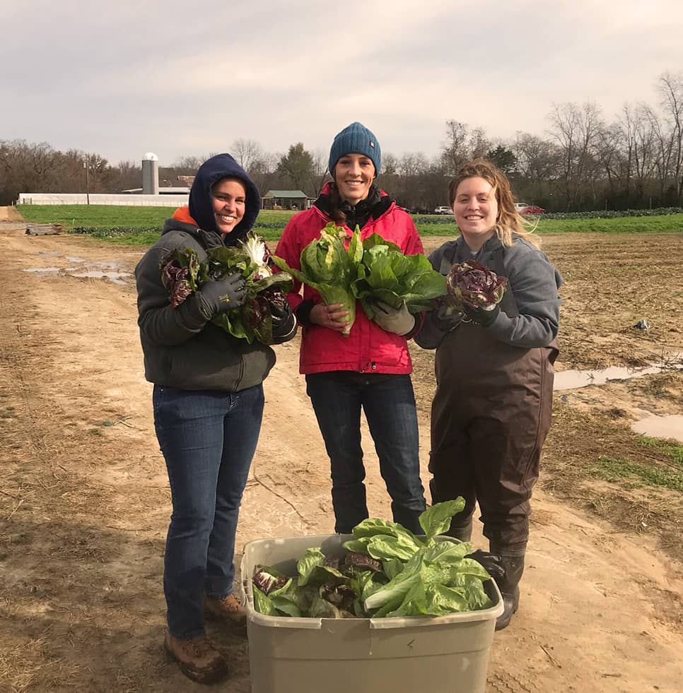 Red River employees smiling and holding local produce